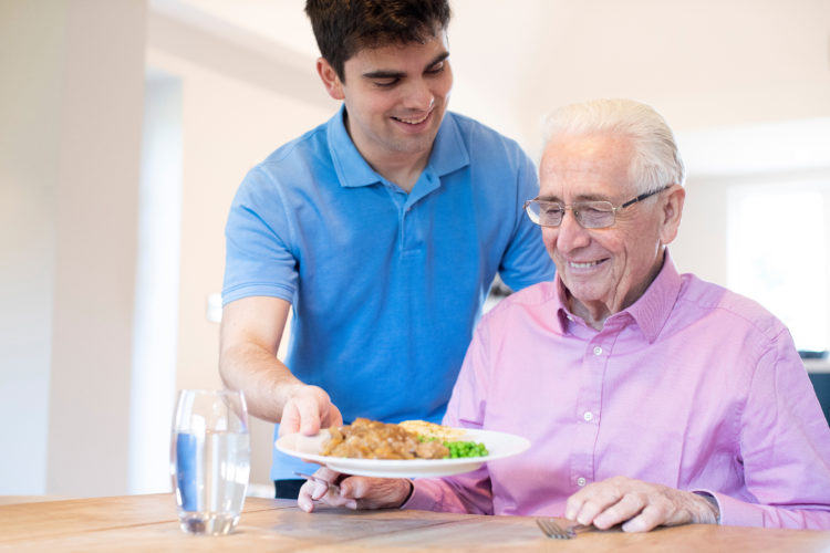 personnel d'ehpad servant le repas à une personne âgée